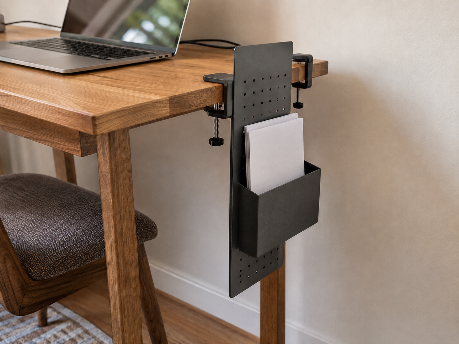 Clamp-mounted vertical paper holder attached to a compact desk edge with two mounting clamps visible and the main work surface clear.